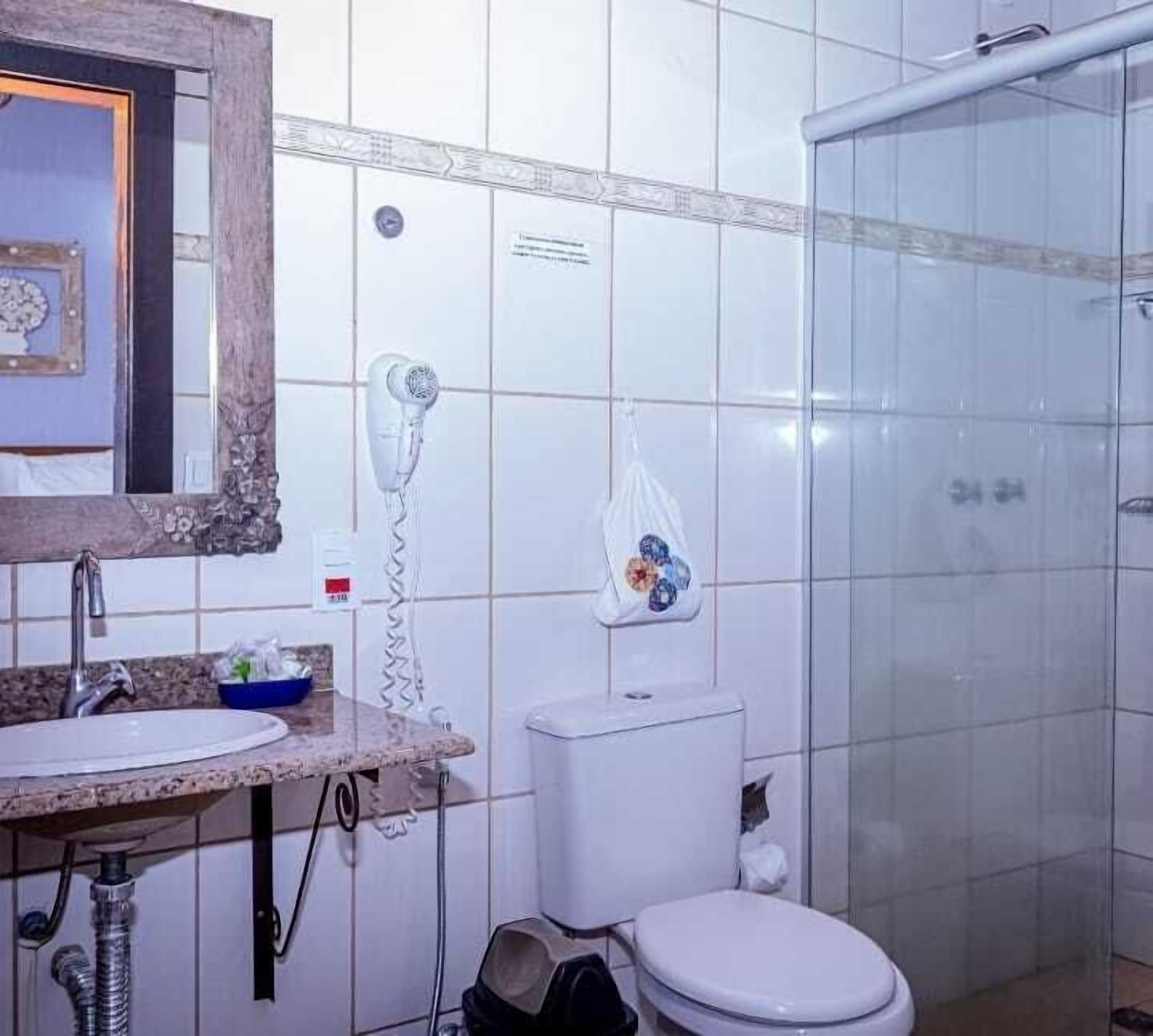 Uma casa de banho com lavatório, sanita e chuveiro.