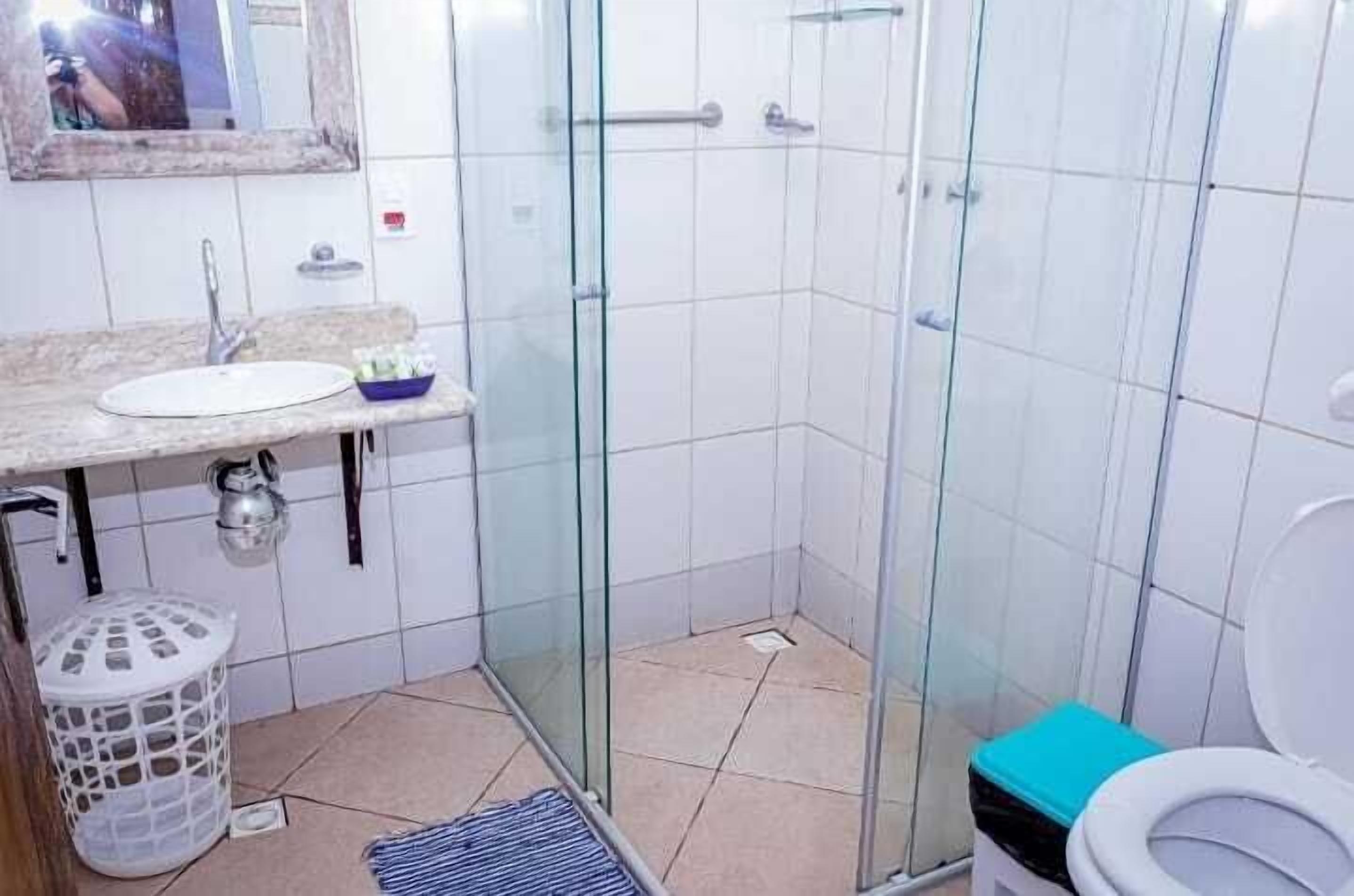 A bathroom with a glass shower enclosure, a sink, and a toilet.