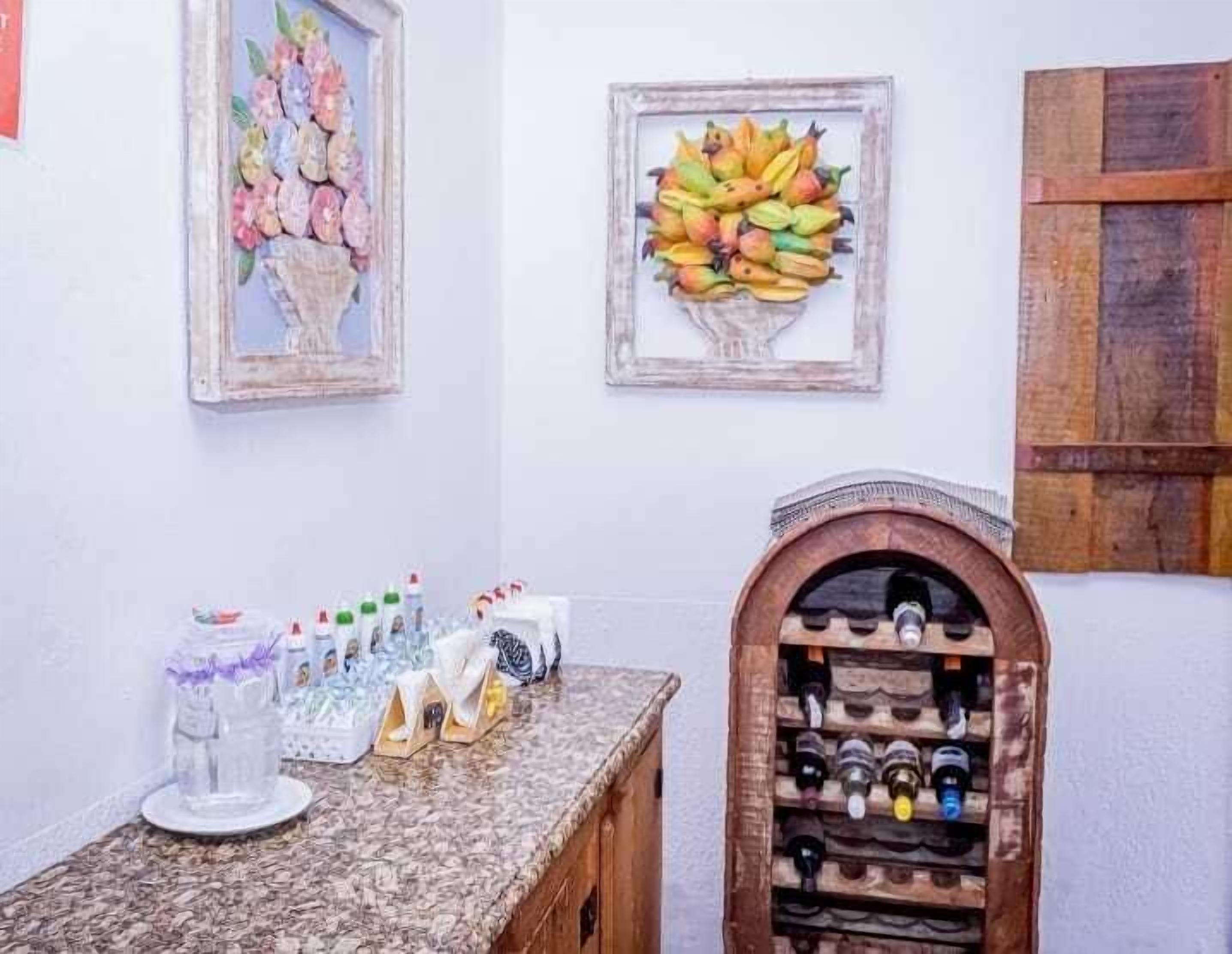 Una habitación con encimera de mármol, un botellero y dos cuadros enmarcados.