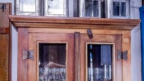 Een houten kast met glazen deuren, gevuld met gestapelde witte borden en kommen.