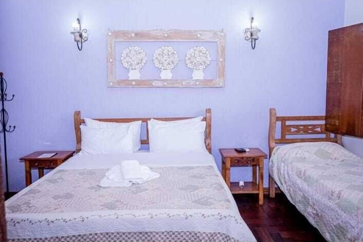 A bedroom with a large bed, two bedside tables, a wooden headboard, and a wall-mounted picture frame.