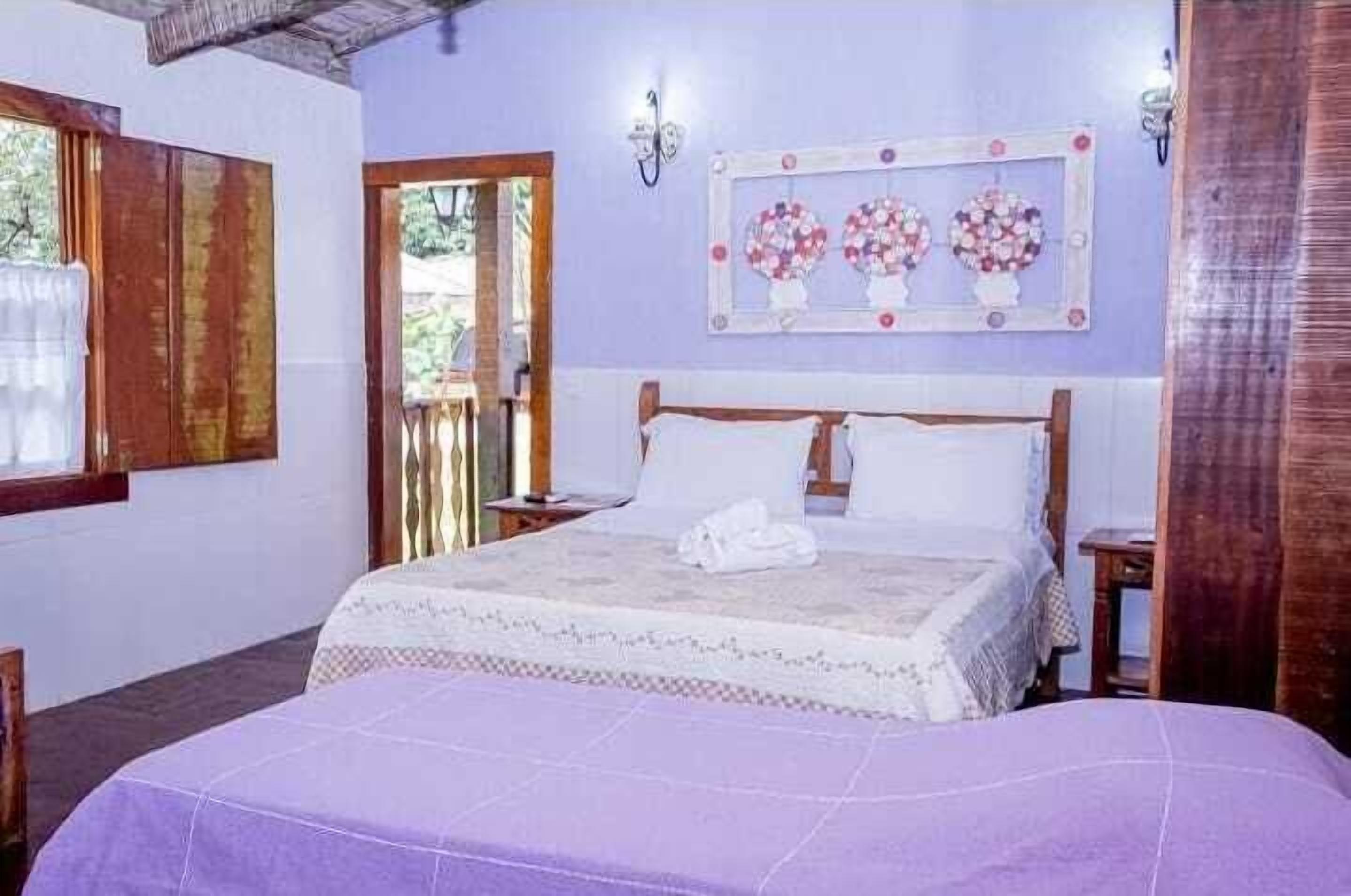 A bedroom with a bed, a nightstand, a mirror, and a window.