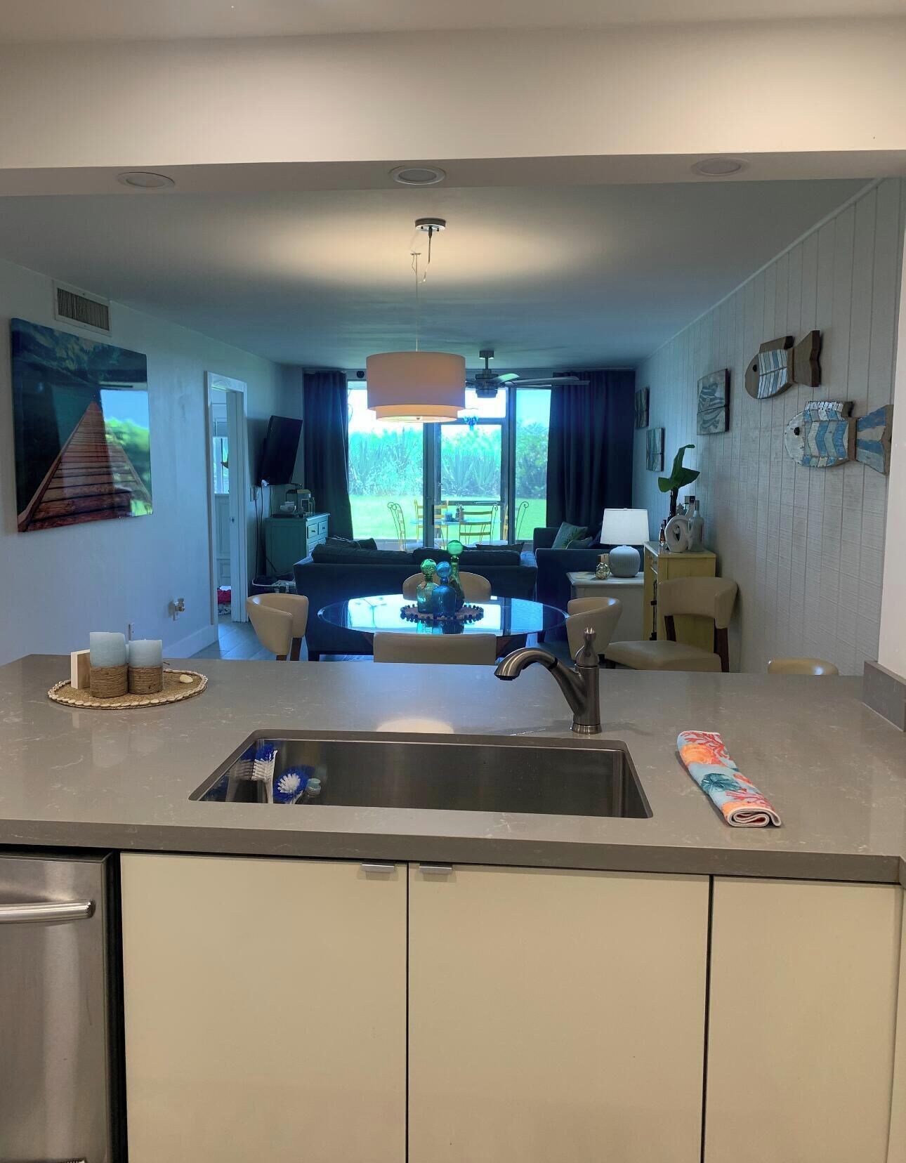 Een moderne keuken met een groot eiland, een eethoek met tafel en stoelen, en een zithoek met een bank en televisie.