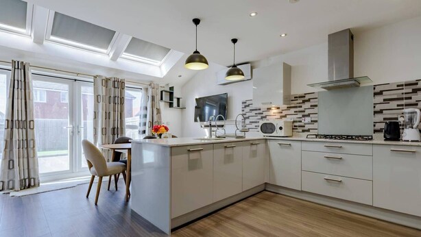 Una cocina moderna con una isla central, electrodomésticos integrados y un amplio ventanal con cortinas.