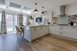 Una cocina moderna con una isla central, electrodomésticos integrados y un amplio ventanal con cortinas.