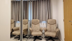Una sala de conferencias con cuatro sillas color beige, un panel de vidrio, un radiador y una puerta de madera.