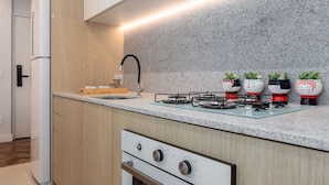 A modern kitchen with wooden cabinets, a granite countertop, a built-in oven, a gas stove, and a stainless steel sink. - Luxury in Barra da Tijuca Near the Olympic Park Av806 (Rio de Janeiro)