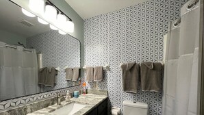 A bathroom with a marble sink, a toilet, and patterned wallpaper. - The Boho Blast of Winston-Salem (Winston-Salem)
