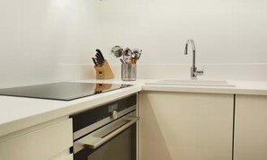 A modern kitchen with a black induction cooktop, a stainless steel sink, and a knife block with various utensils.