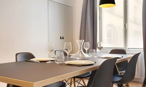 A dining area with a long table, chairs, and wine glasses.