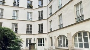 Un edificio de varios pisos con un patio que cuenta con suelo adoquinado y una jardinera central.