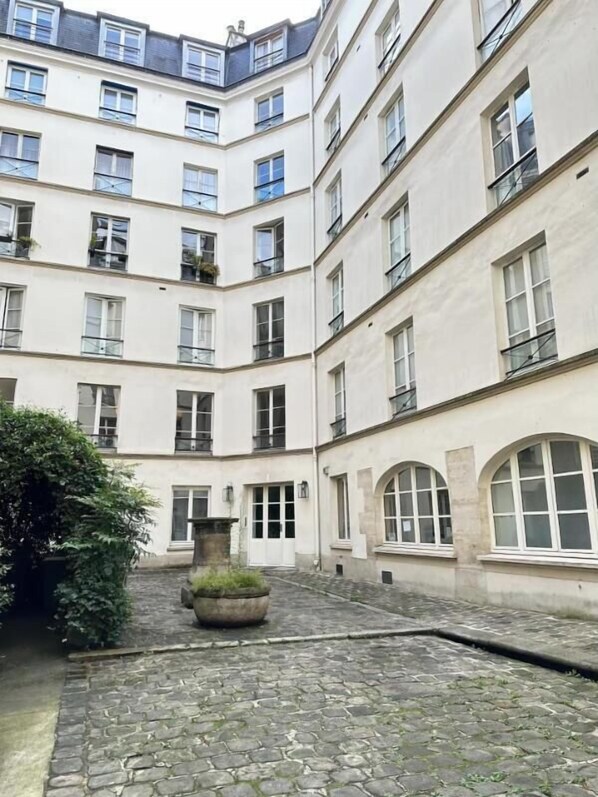 A multi-story building with a courtyard featuring cobblestone flooring and a central planter.