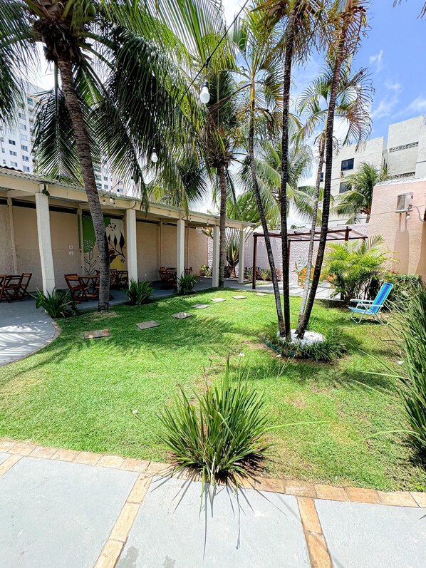 A courtyard with palm trees, a covered seating area, and a grassy lawn. - Caju Villa (Aracaju)