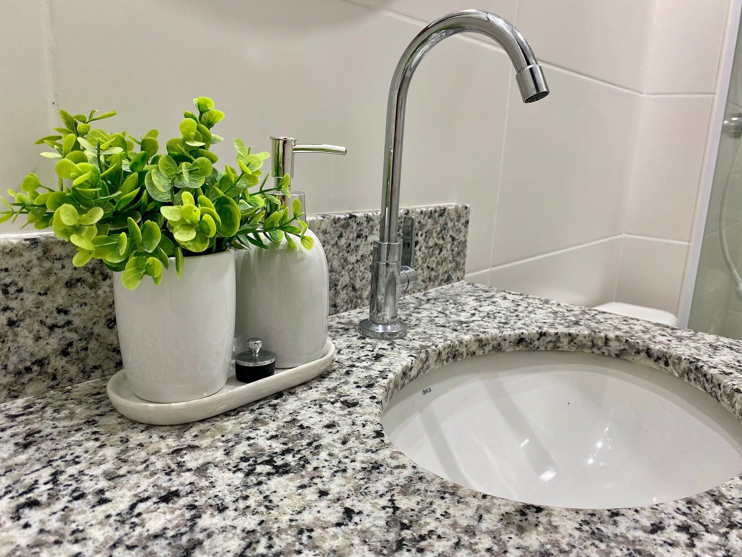 A bathroom with a granite countertop, a white sink, and a modern faucet.