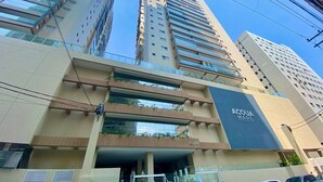 A multi-story building with a prominent 'ACQUA MARE' sign, large windows, and a modern architectural design. - Residencial Acquamare (Praia Grande)