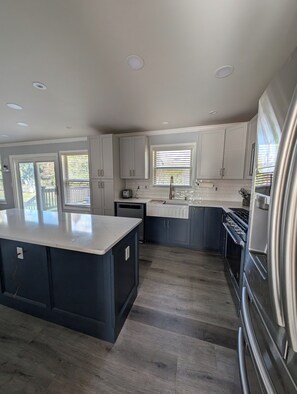 Una cocina moderna con armarios blancos, una isla central y un refrigerador de acero inoxidable.