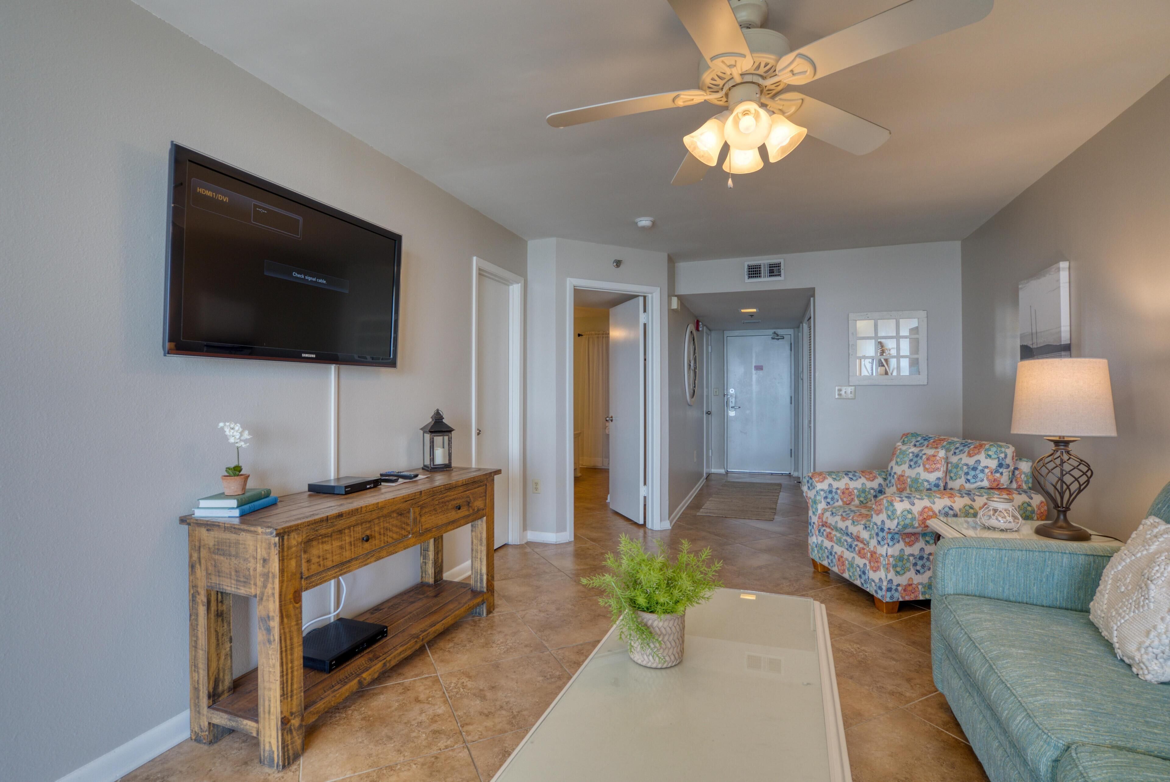 A living room with a television, wooden console table, and a ceiling fan.