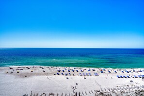 A beach with rows of blue and yellow umbrellas, a sandy shore, and the ocean in the background. - Phoenix IV 4112 (Orange Beach)