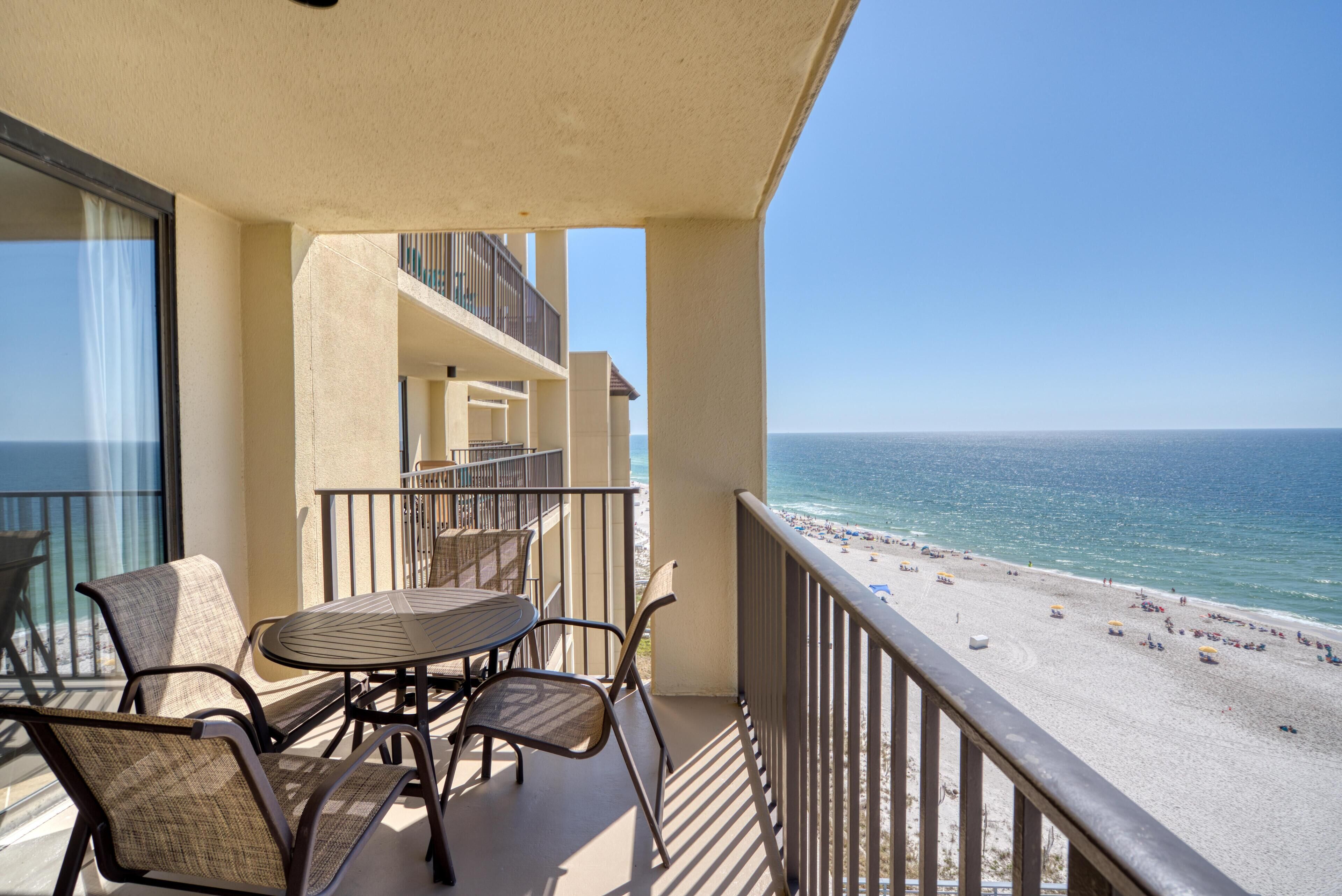 Un balcon avec une table et des chaises donnant sur une plage.
