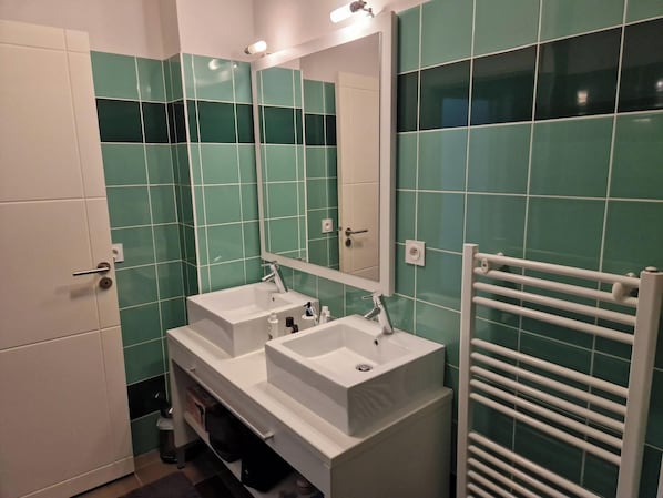A modern bathroom with two sinks, a mirror, and a towel rack. - Charming vacation apartment with terrace, pool and parking space - ideal for families (Baden)