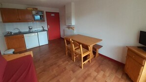 Un espacio habitable compacto con kitchenette, comedor y televisor.
