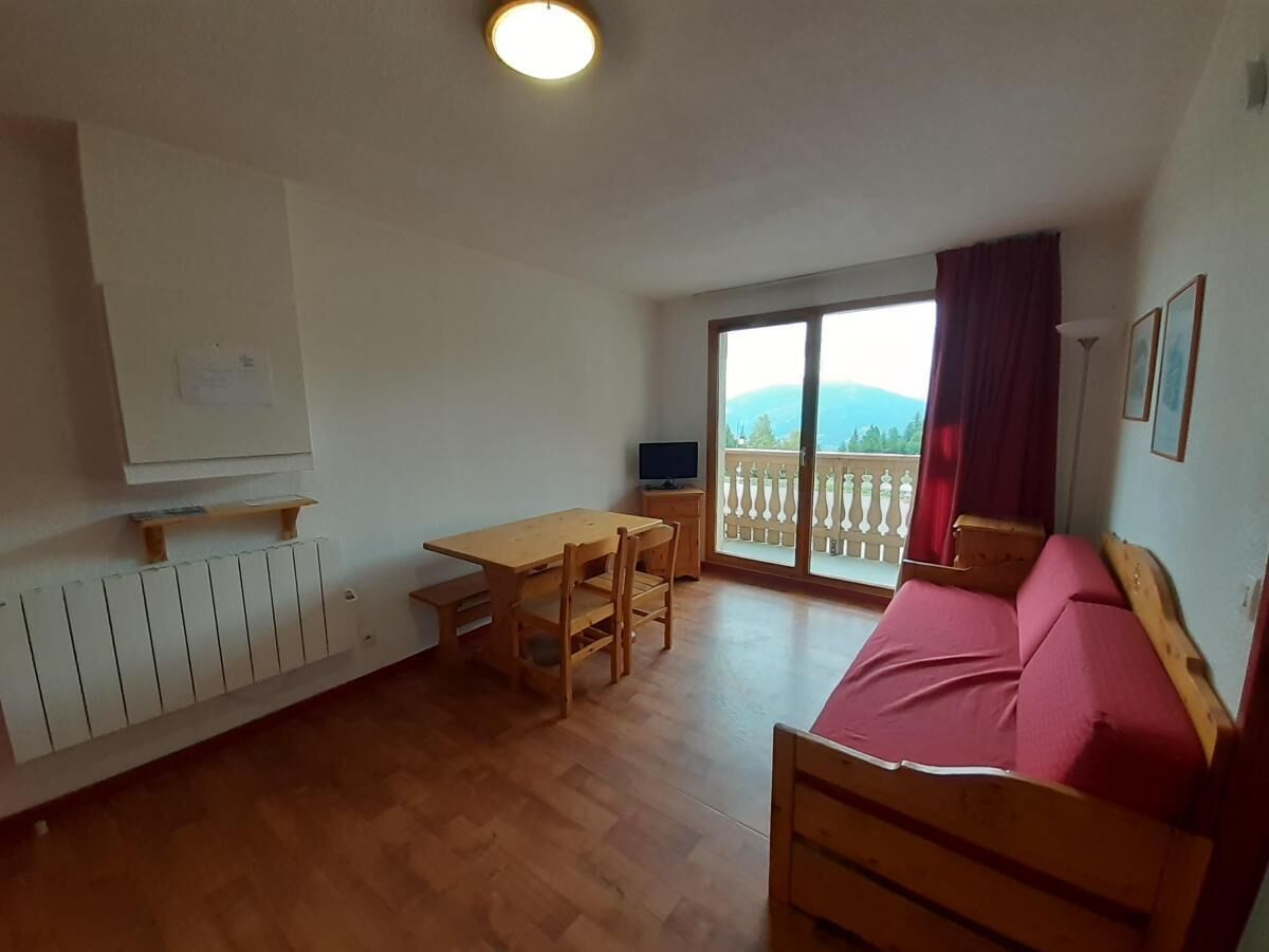 Ein Zimmer mit einem hölzernen Bett, einem Holztisch mit Stühlen, einem Fernseher und einem Balkon mit Blick.