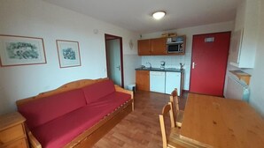 Un espacio habitable compacto con sofá, mesa de comedor y kitchenette.