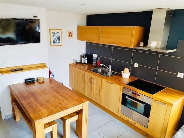 Une cuisine compacte avec des meubles de rangement en bois, un four encastré et un petit évier.