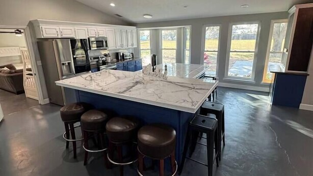 A spacious kitchen with a large island, bar stools, and a view of the outdoors. - The Bunkhouse at Origins Ranch (Plant City)