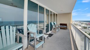 Un balcone con vista sull'oceano, dotato di diverse poltrone Adirondack e un divano in vimini.