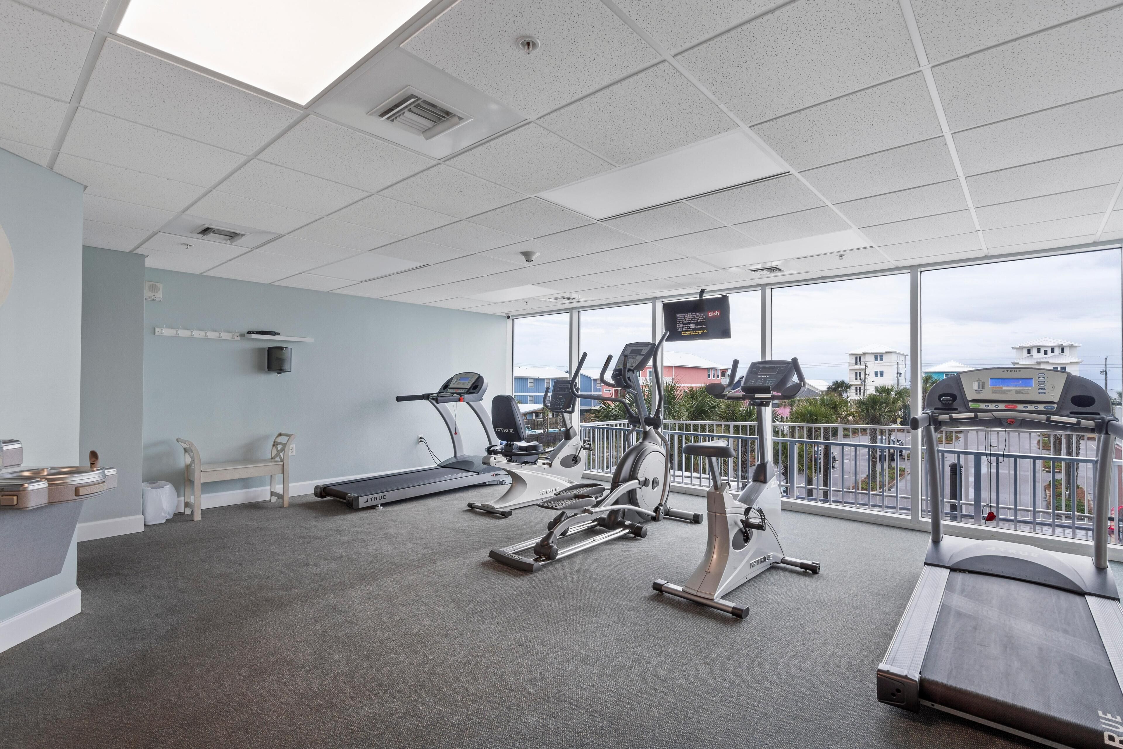 A gym with treadmills, stationary bikes, and a bench.