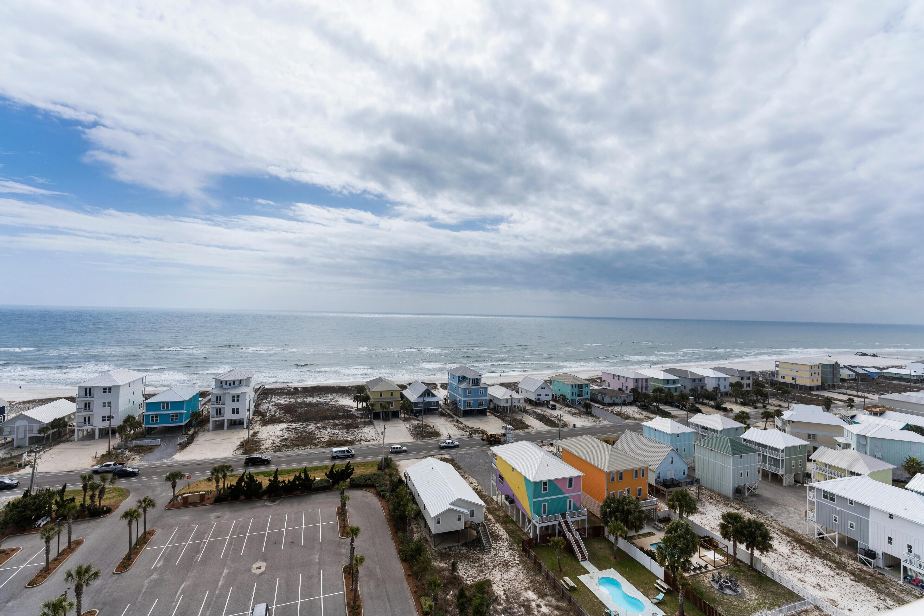 Un quartier résidentiel situé sur la côte, avec des maisons à proximité de la plage, un parking et une vue dégagée sur l’océan.
