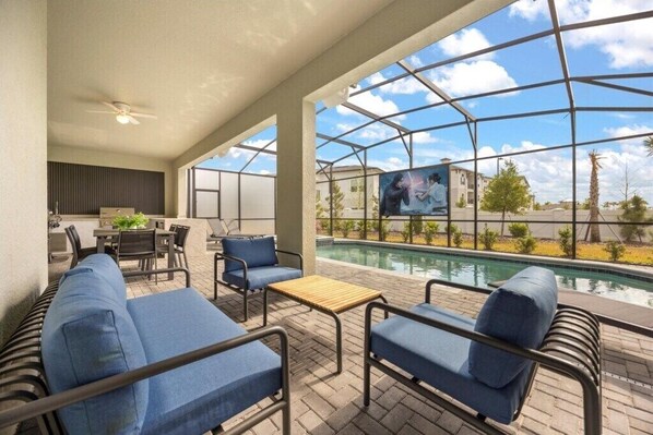 Relax by the pool in a comfortable lounge area with cushioned seating and a small table.