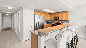 Una cocina moderna con armarios de madera, un refrigerador de acero inoxidable, un microondas y una encimera de granito.
