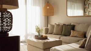 A living room with a sofa, ottoman, lamp, and a vase with flowers. - Luxury apartment in Flic en Flac (Flic en Flac)