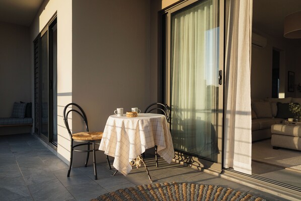 A balcony with a table and chairs, a sofa, and a sliding glass door.