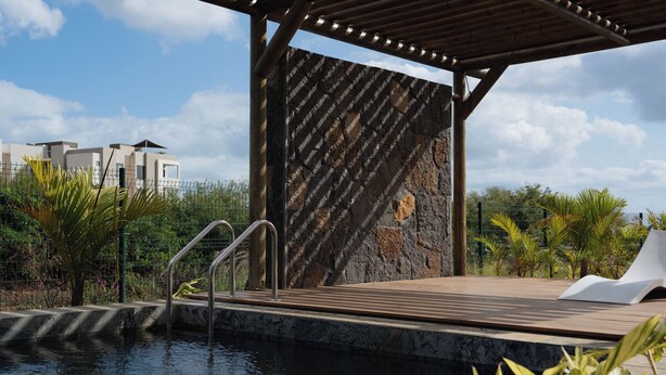 A pool area with a wooden deck, metal railings, and a stone wall. - Luxury apartment in Flic en Flac (Flic en Flac)