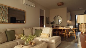 A modern living room with a sofa, ottoman, and a dining area with a table and chairs. - Luxury apartment in Flic en Flac (Flic en Flac)