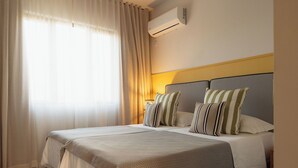 A hotel room with a bed, curtains, an air conditioner, and a bedside lamp. - Luxury apartment in Flic en Flac (Flic en Flac)