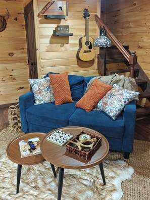 A cozy room with a blue sofa, a wooden coffee table, and a guitar on the wall.