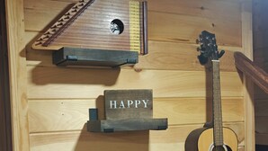 A guitar, a metronome, and a 'HAPPY' sign on a wooden wall.