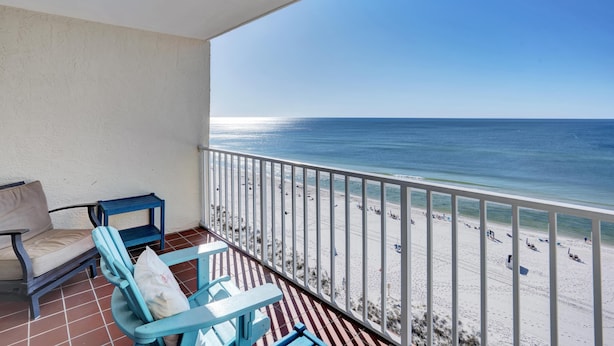 Un balcon avec vue sur la plage, comprenant un canapé, des fauteuils et une petite table.