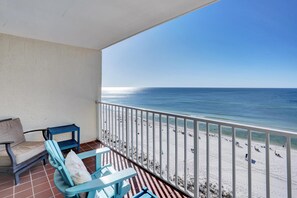 A balcony with a view of the beach, featuring a sofa, chairs, and a small table. - Seacrest 904 (Gulf Shores)