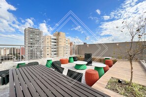 Enjoy panoramic views of the city skyline from this rooftop space, featuring a variety of seating options and a small tree for added greenery.