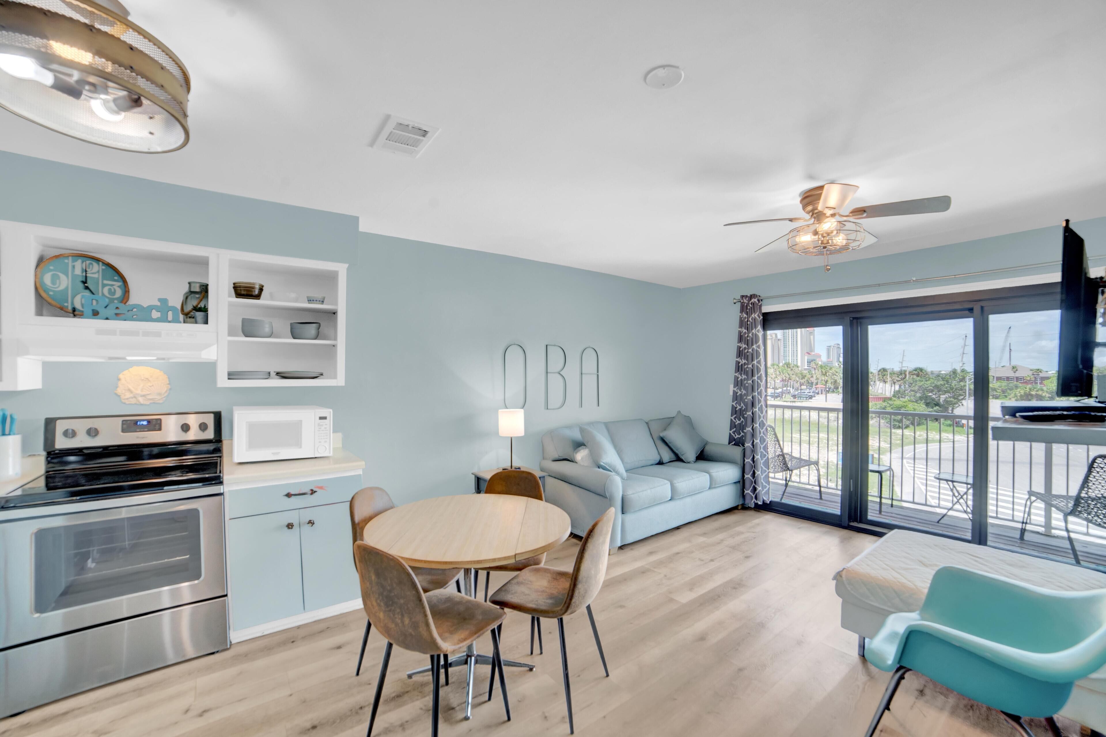 Une cuisine moderne équipée d’un four à micro-ondes, d’une cuisinière et de placards, un coin repas avec une table ronde et des chaises, un canapé et un balcon avec vue.