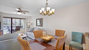 A dining area with a wooden table, wicker chairs, and a chandelier. - Seaside Beach & Racquet 2303 (Orange Beach)