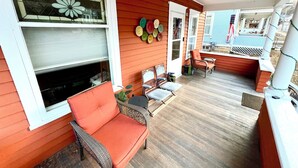 A covered porch with wicker furniture, a fire pit, and a view of the backyard.
