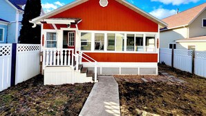 A red and white house with a porch, a front door, and a small staircase leading to the entrance.
