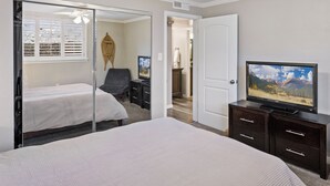 A bedroom with a bed, a TV, a dresser, and a mirror.