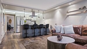 A modern kitchen with a central island, bar stools, and pendant lighting.